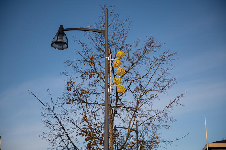 Lyhtypylväässä koriste, jossa pieniä keltaisia koristepalloja.