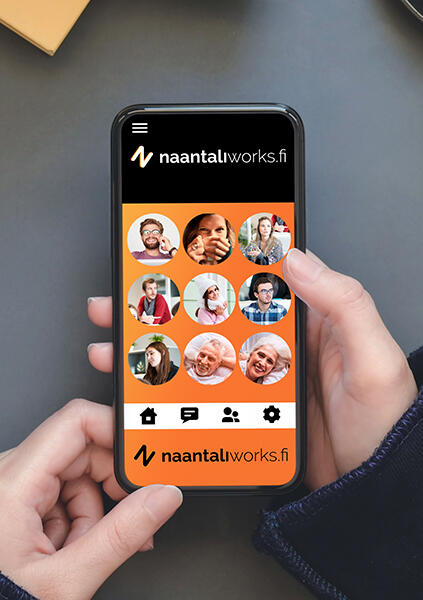 Henkilö pitelee käsissään puhelinta, jossa on auki NaantaliWorks-sovellus. Sovelluksen värimaailma on musta-oranssi, ruudulla näkyy useita ihmisten kasvoja.