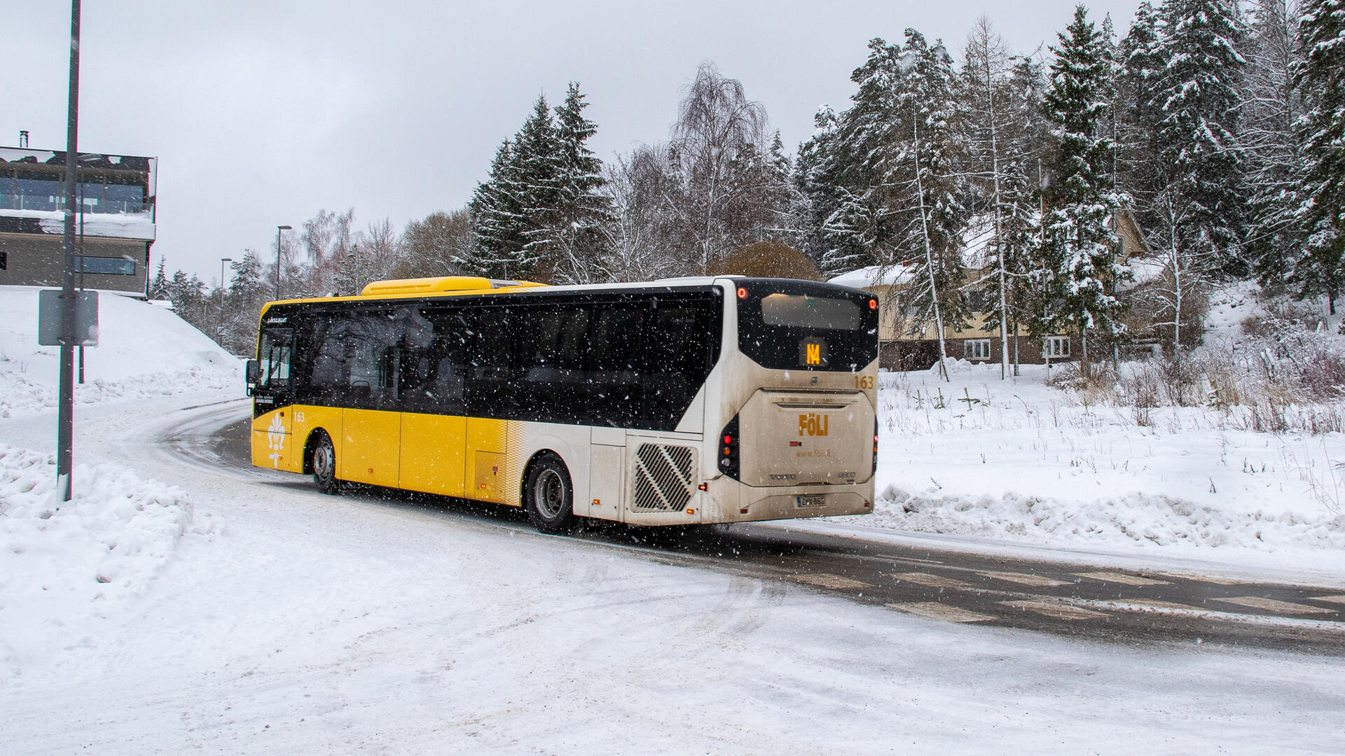 Fölin bussi numero N4 ajaa kevyessä lumisateessa loivaa mäkeä ylös Luonnonmaalla.
