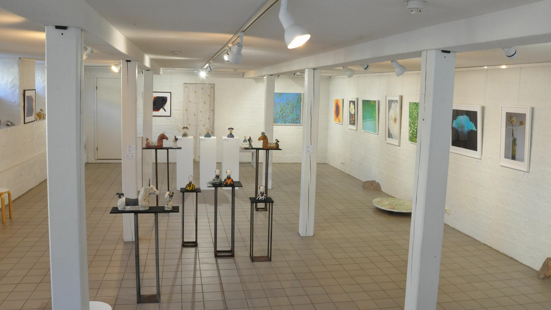 galleriatila jossa näkyy kuvia seinillä ja veistosjalustoilla pienoisveistoksia