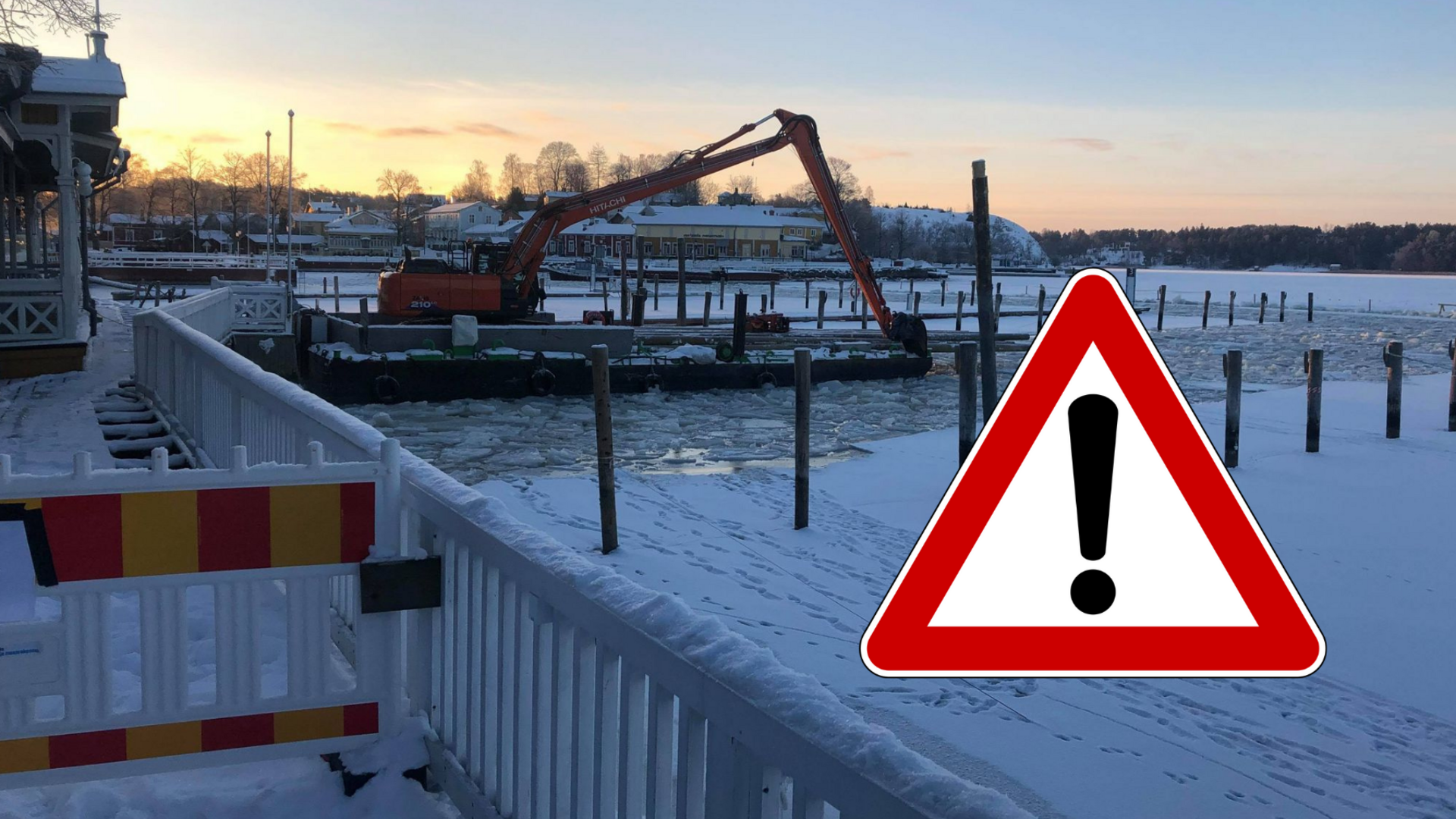 Aurinko nousee Vanhankaupungin rannassa, jossa työmaalautta seisoo rikkoutuneen jään keskellä. Kuvaan lisätty varoitussymboli.