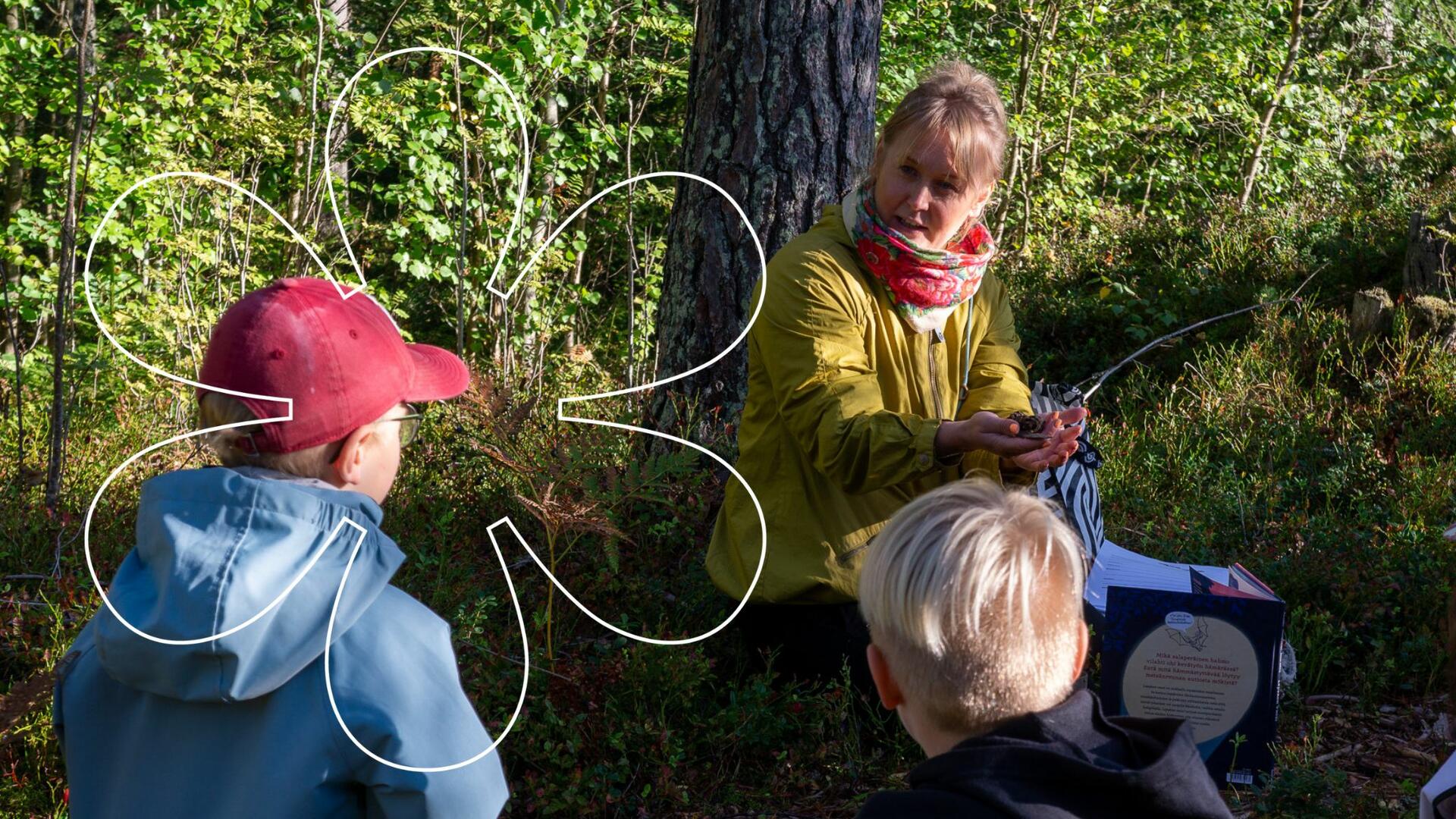 Lapset istuvat metsässä ja katsovat, kun Veera Vähämaa opastaa. Kuvan päällä Onnellinen aurinko -elementti.