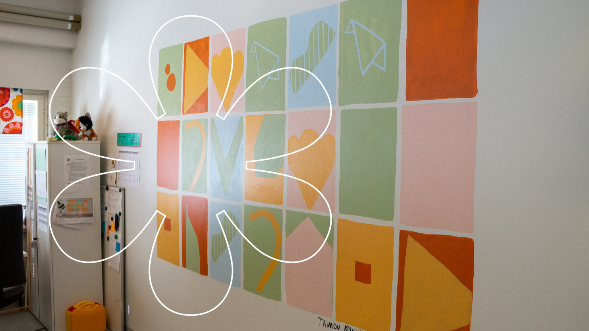 Seinälle on maalattu kolmeen riviin neliöitä, joiden sisällä on erilaisia muotoja. Kuvan päällä Onnellinen aurinko -elementti.